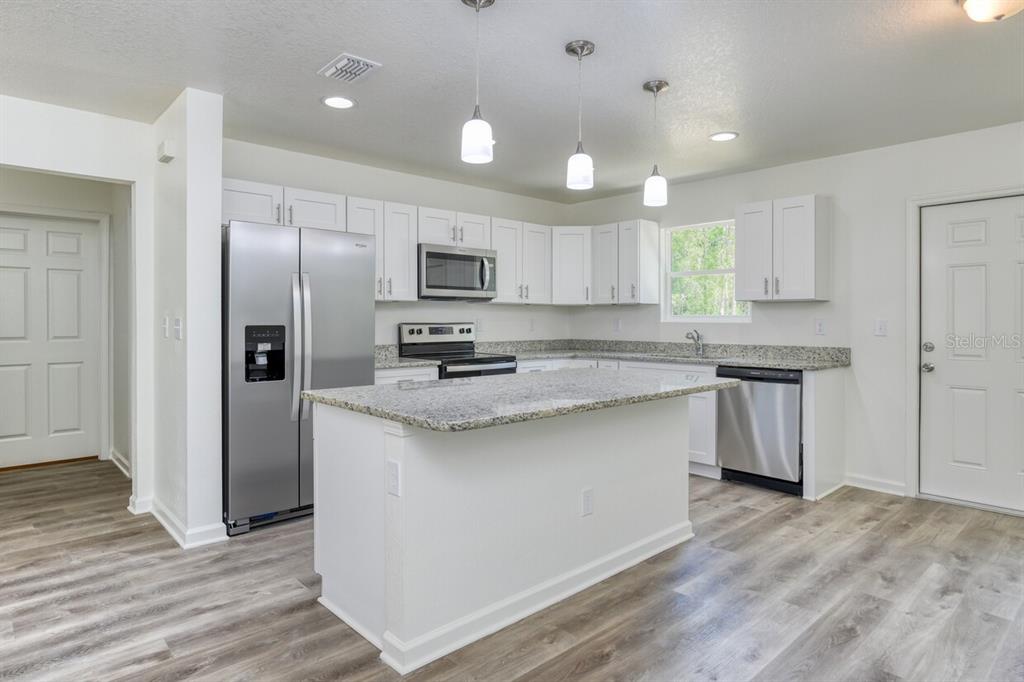 4840 Kenneth Street Hastings, FL 32145 - Photo 3 of 22 a kitchen with kitchen island granite countertop a sink stove and refrigerator