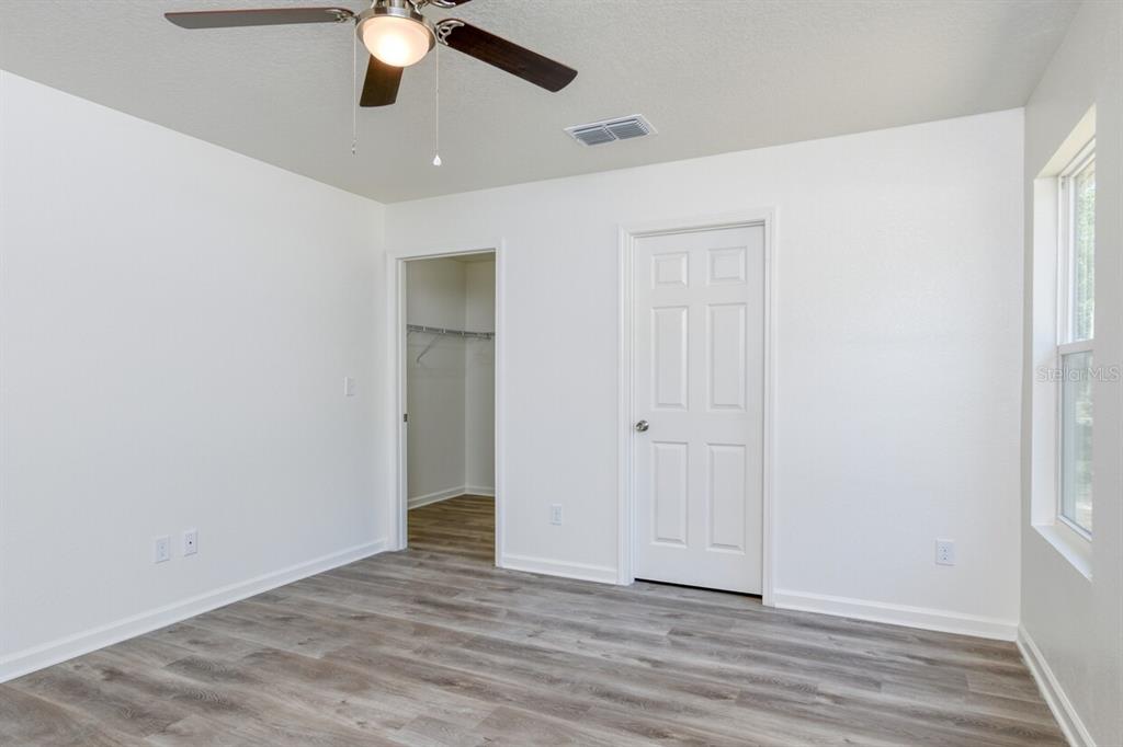 4840 Kenneth Street Hastings, FL 32145 - Photo 6 of 22 an empty room with wooden floor chandelier fan and windows