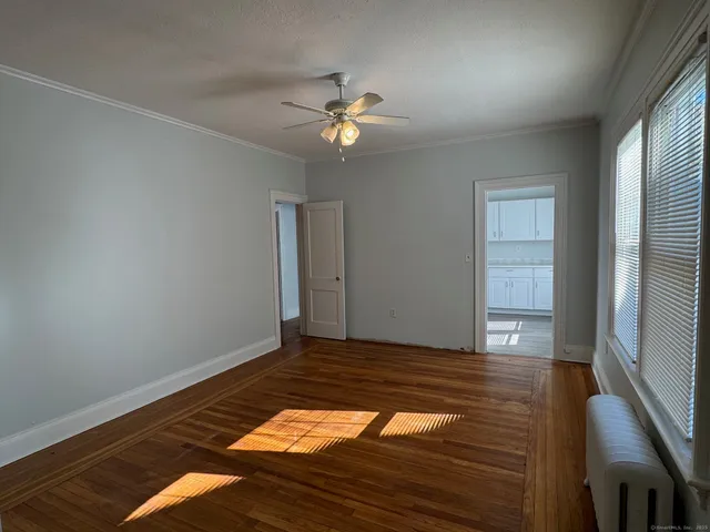a view of empty room with wooden floor and fan