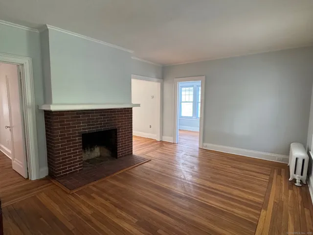 an empty room with wooden floor fireplace and windows