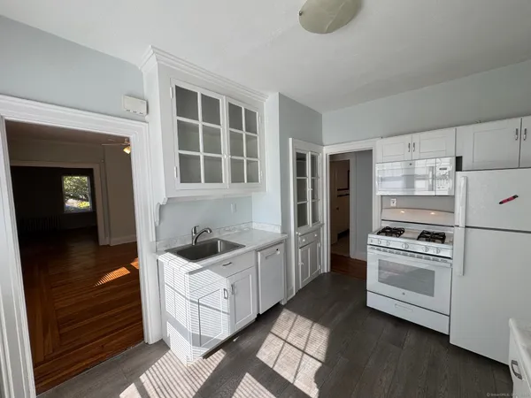a kitchen with white cabinets and appliances