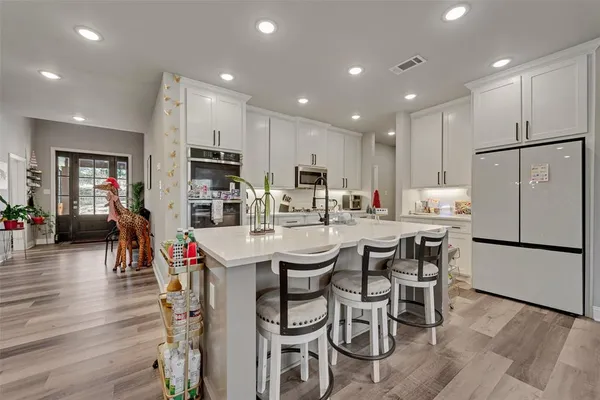 a kitchen with stainless steel appliances kitchen island granite countertop a dining table chairs refrigerator and sink