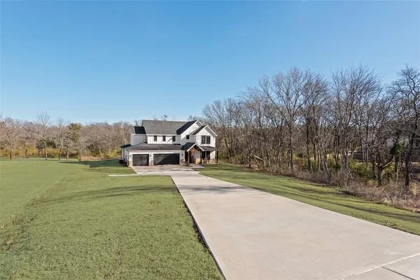 a front view of a house with a yard and trees