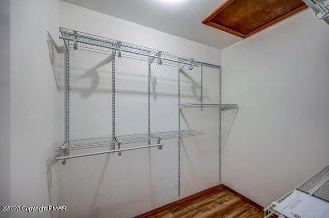 a view of an empty room with wooden floor and a ceiling fan