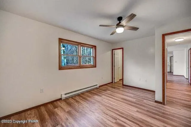 a view of empty room with wooden floor and fan
