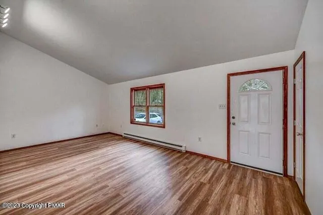 an empty room with wooden floor and windows