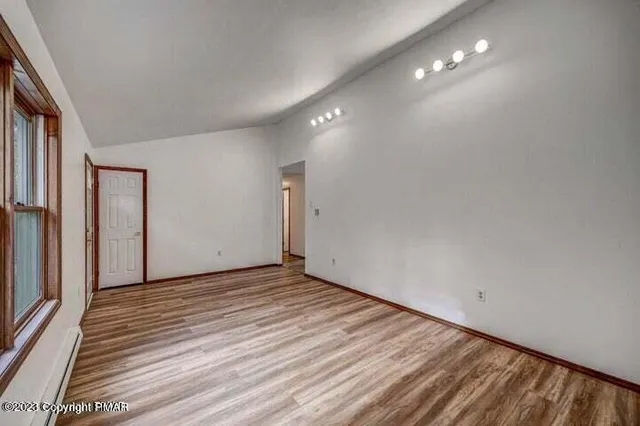 a view of an empty room with wooden floor and a window