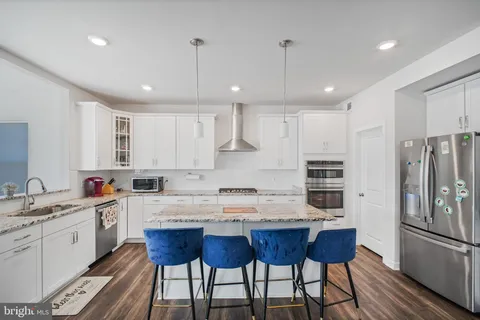 a kitchen with stainless steel appliances granite countertop a stove top oven a sink dishwasher a dining table and chairs