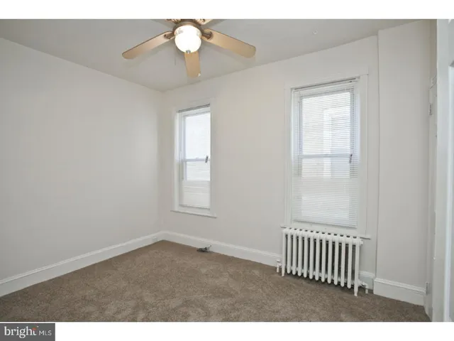 an empty room with windows and ceiling fan