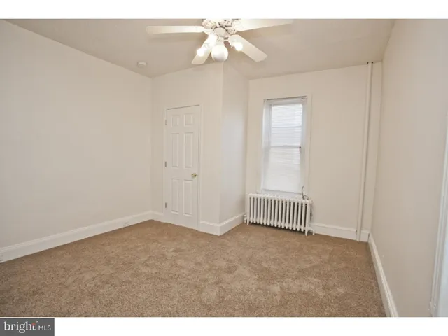 a view of an empty room with chandelier fan