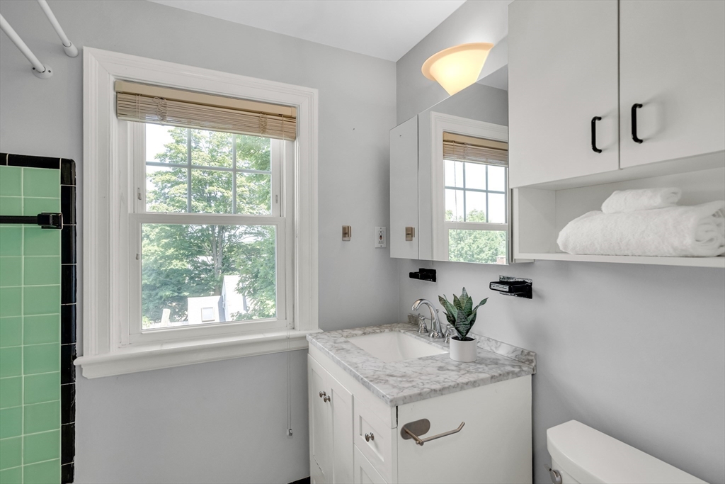 16 Roundwood Road Newton, MA 02464 - Photo 28 of 41 a bathroom with a granite countertop sink a toilet and a window