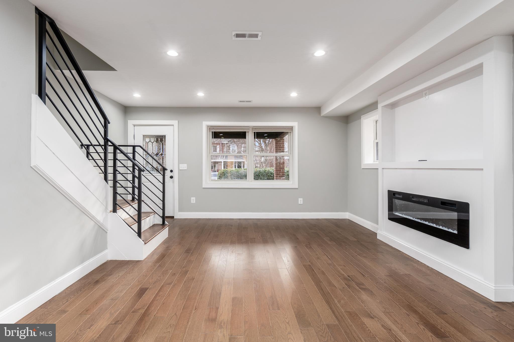 928 Perry Place Northeast Washington, DC 20017 - Photo 7 of 36 an empty room with wooden floor fireplace and windows