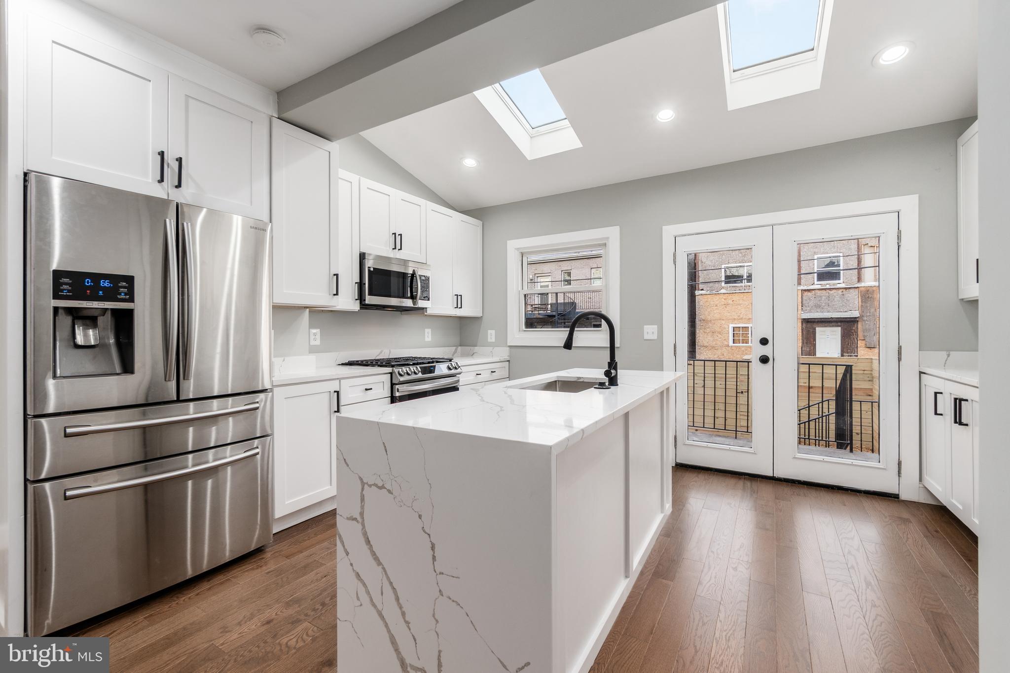 928 Perry Place Northeast Washington, DC 20017 - Photo 10 of 36 a kitchen with stainless steel appliances a refrigerator a stove a sink cabinets and a wooden floor