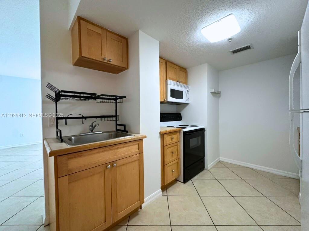 2630 Southwest 28th Street, Unit 44 Miami, FL 33133 - Photo 7 of 12 a kitchen with stainless steel appliances a stove microwave and cabinets