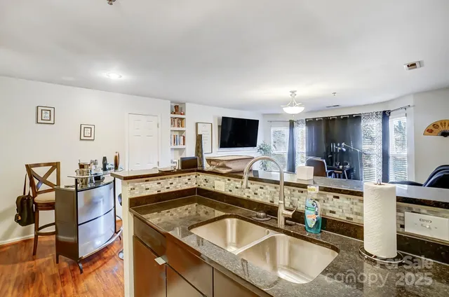 a kitchen with stainless steel appliances granite countertop a sink and a stove top oven with wooden floor