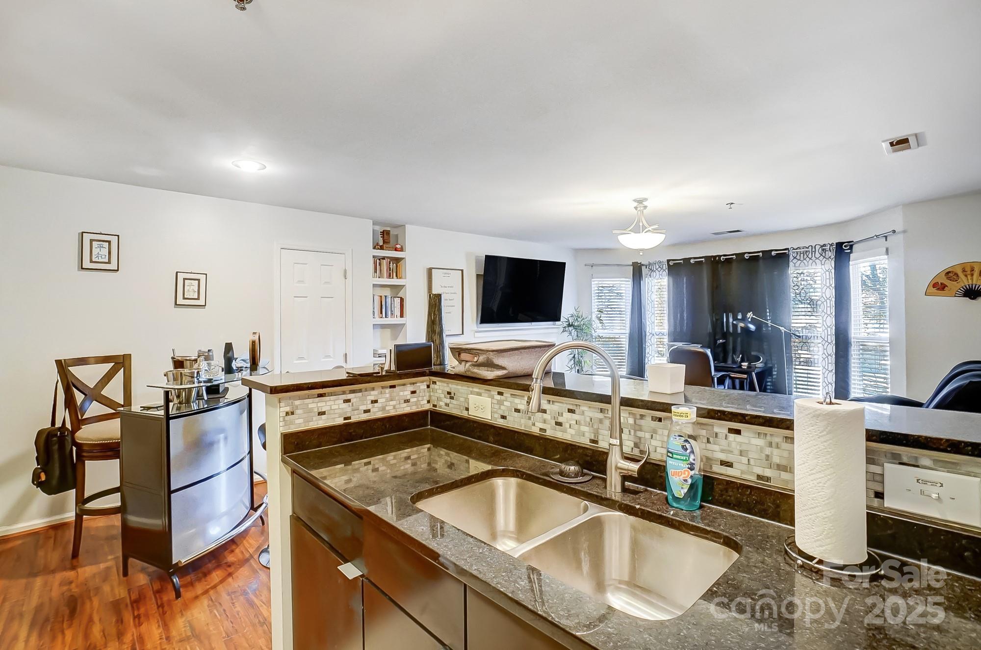 a kitchen with stainless steel appliances granite countertop a sink and a stove top oven with wooden floor