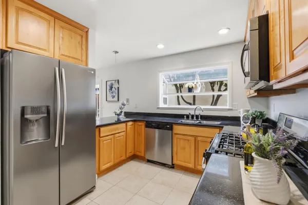 a kitchen with stainless steel appliances granite countertop a refrigerator a sink a stove and a wooden cabinets