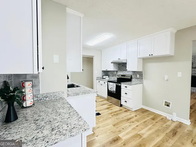 a kitchen with granite countertop a sink stove and cabinets