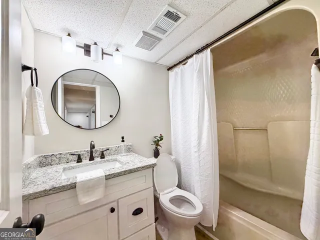 a bathroom with a granite countertop toilet sink and mirror