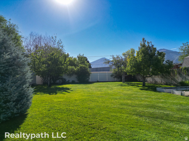 475 South 300 East Payson, UT 84651 - Photo 7 of 12 Expansive fenced backyard featuring a manicured lawn, mature trees, and mountain scenery