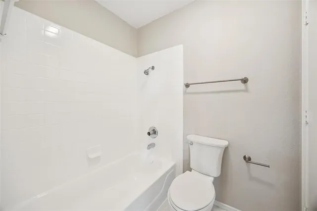 a white toilet sitting next to a bath tub