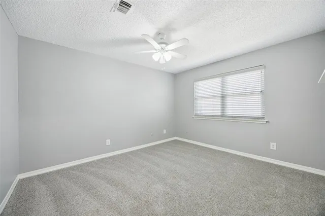 an empty room with a window and a fan