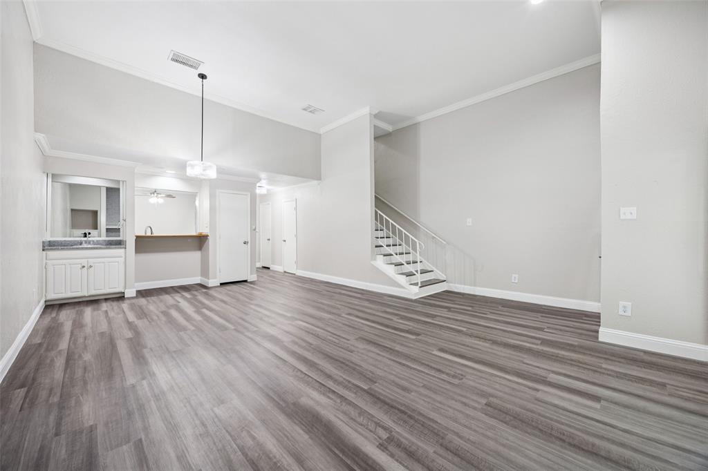 207 East Harwood Road, Unit 14 Euless, TX 76039 - Photo 6 of 28 a view of an empty room with wooden floor and a kitchen
