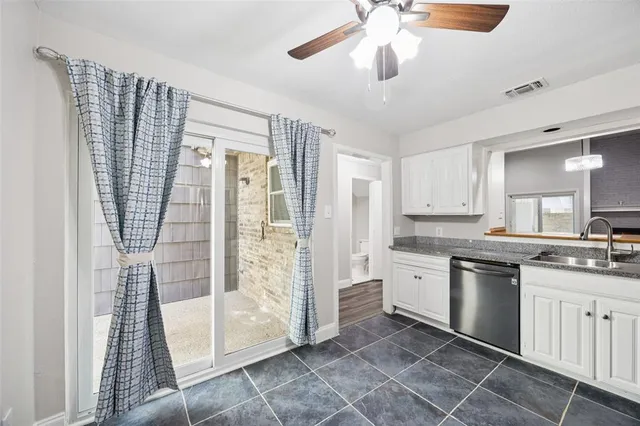 a kitchen with a sink dishwasher a refrigerator and white cabinets