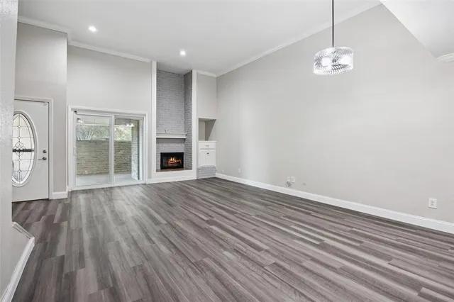 an empty room with wooden floor fireplace and windows