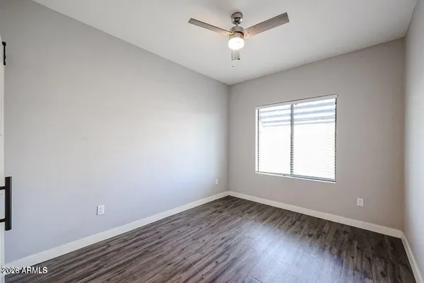 an empty room with wooden floor ceiling fan and windows
