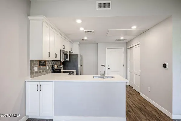 a view of a kitchen with kitchen island white cabinets and stainless steel appliances