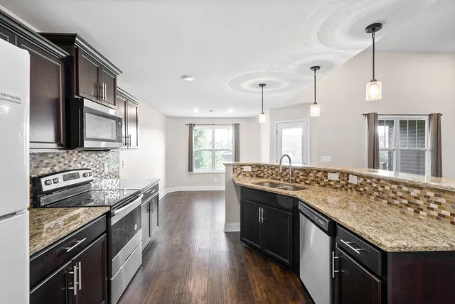 a kitchen with stainless steel appliances granite countertop a stove and a wooden floors