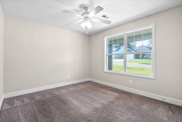 an empty room with windows and fan