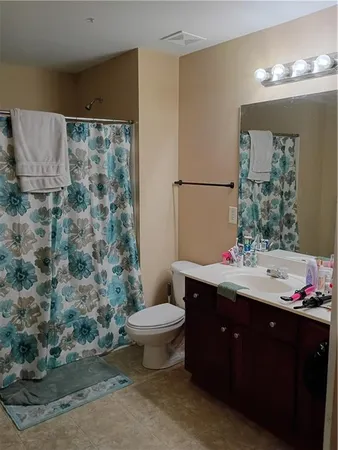 a bathroom with a granite countertop sink toilet and mirror