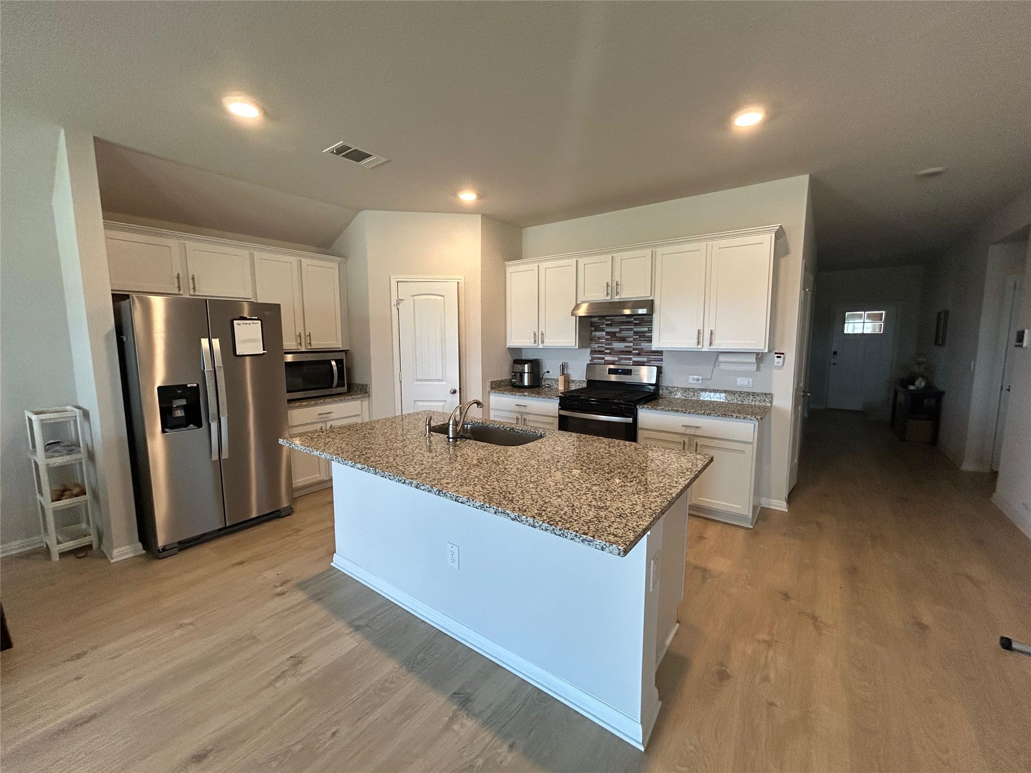 2412 Lightning View Leander, TX 78641 - Photo 3 of 24 A well-appointed kitchen features a central island with granite counters and stainless steel appliances.
