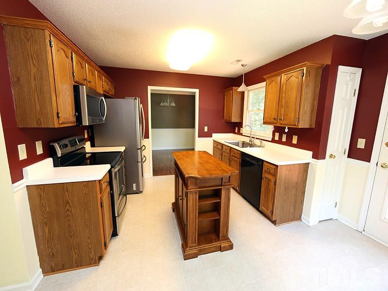3505 Singleleaf Lane Raleigh, NC 27616 - Photo 3 of 14 a kitchen with stainless steel appliances a stove a refrigerator a sink dishwasher and wooden cabinets with wooden floor