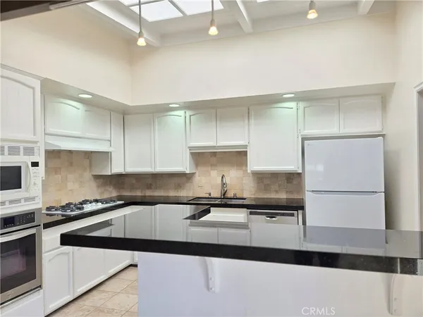 a kitchen with granite countertop a sink a stove and refrigerator