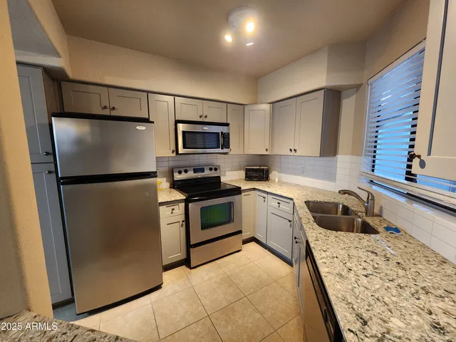 a kitchen with stainless steel appliances granite countertop a sink stove and refrigerator