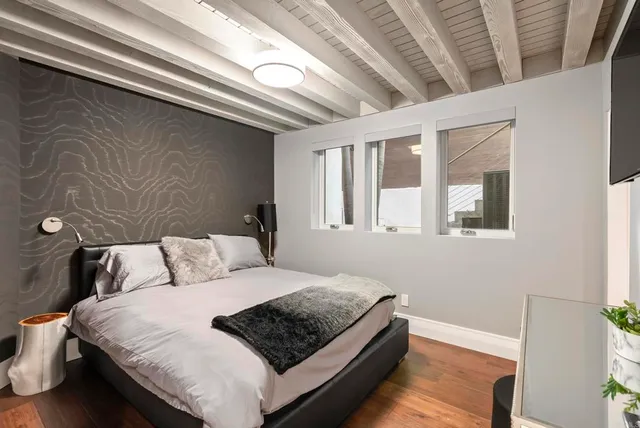 a bedroom with a bed lamp and a large window