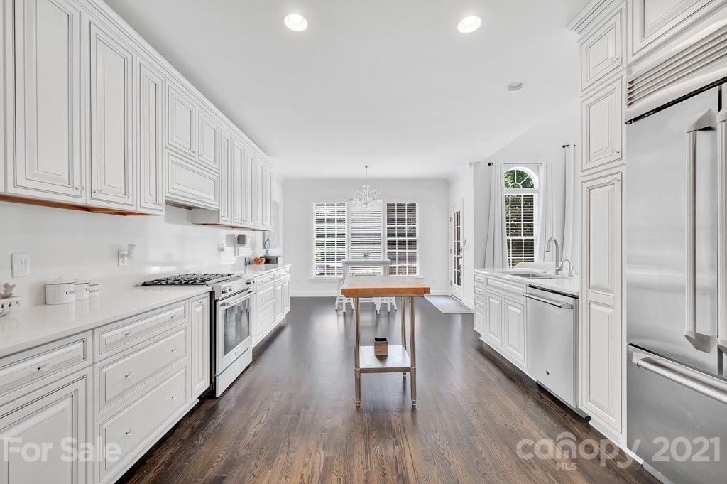 1883 Chestnut Hill Drive Tega Cay, SC 29708 - Photo 7 of 34 a kitchen with granite countertop a refrigerator a sink dishwasher a dining table and chairs with wooden floor