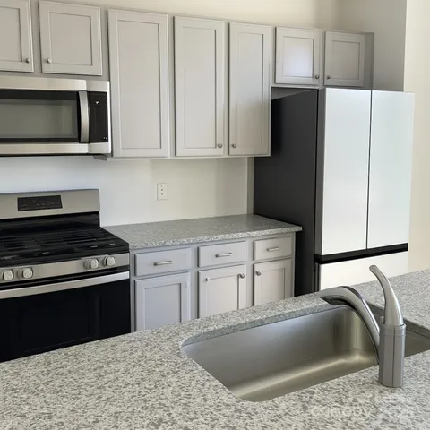 a kitchen with granite countertop a sink stove and refrigerator