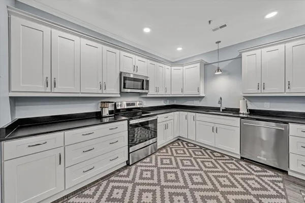 a large white kitchen with stainless steel appliances granite countertop a sink and cabinets