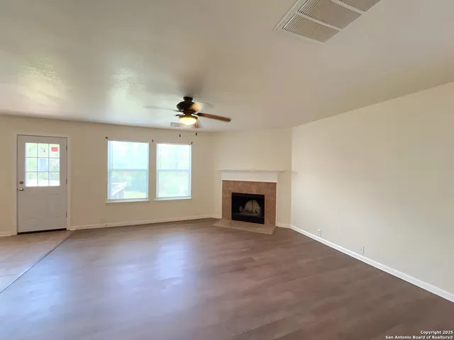 an empty room with windows and fireplace