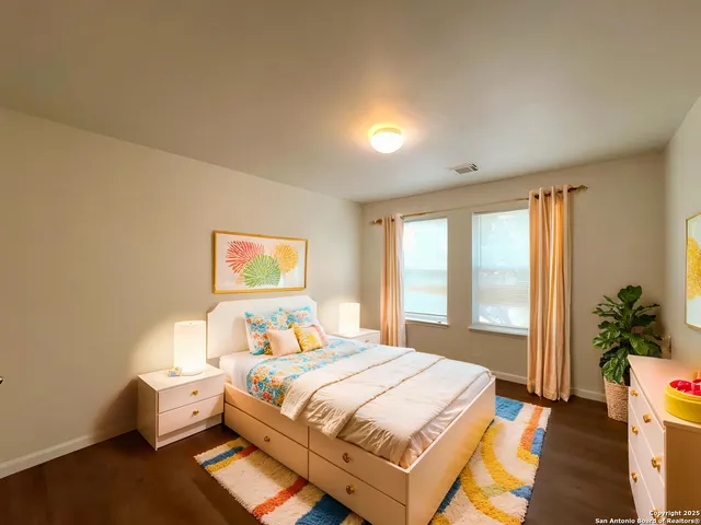 a bedroom with a bed and a potted plant on the dresser