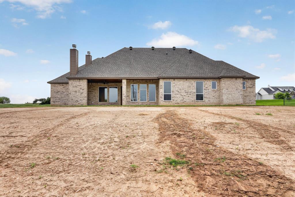 471 Red Bird Drive Springtown, TX 76082 - Photo 32 of 35 Brick exterior featuring multiple tall windows and a covered patio with an outdoor fan