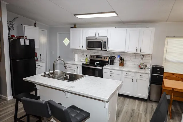 a kitchen with stainless steel appliances granite countertop a sink stove refrigerator and white cabinets