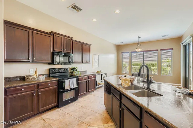 a kitchen with stainless steel appliances granite countertop sink stove top oven and cabinets
