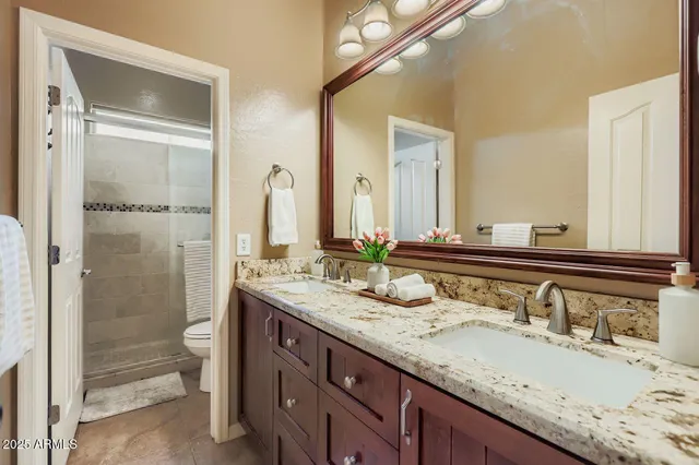 a bathroom with a granite countertop sink double mirror and a shower