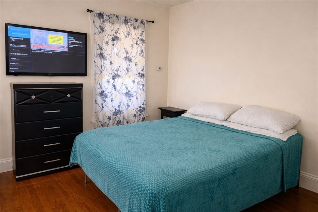 832 Washington Street, Unit 3 Boston, MA 02124 - Photo 4 of 14 a bedroom with a bed and a flat screen tv