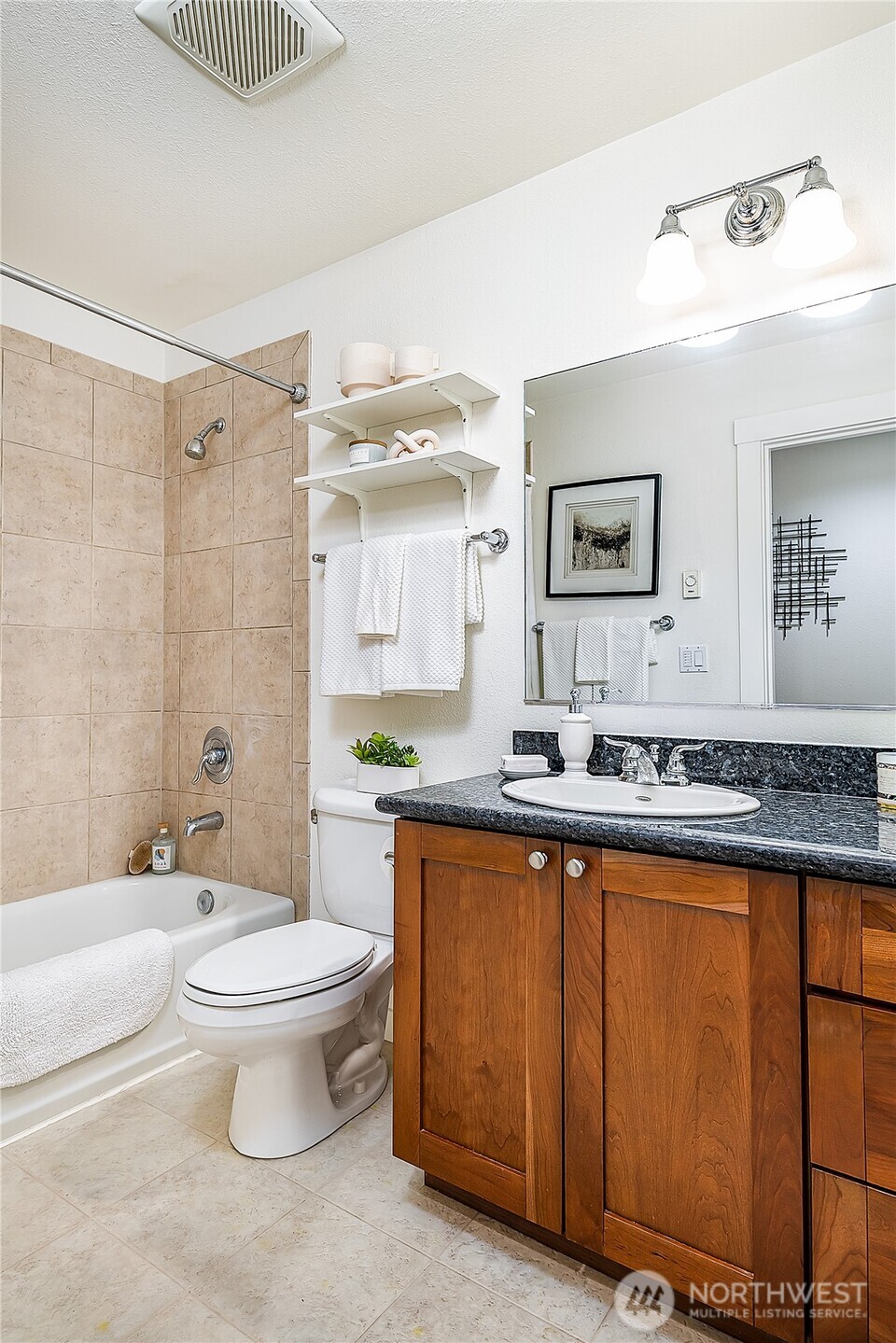 1519 Northwest 59th Street, Unit 101 Seattle, WA 98107 - Photo 17 of 23 a bathroom with a granite countertop sink a toilet a mirror and bathtub